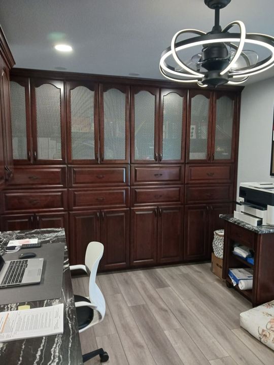 Full-wall cherry office cabinetry with glass-front uppers
