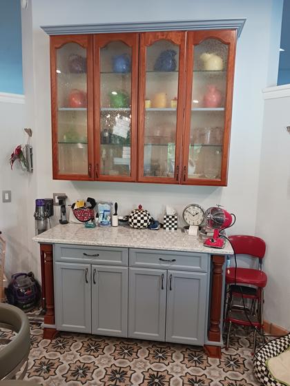 Cherry glass-front hutch above painted base cabinets with turned columns