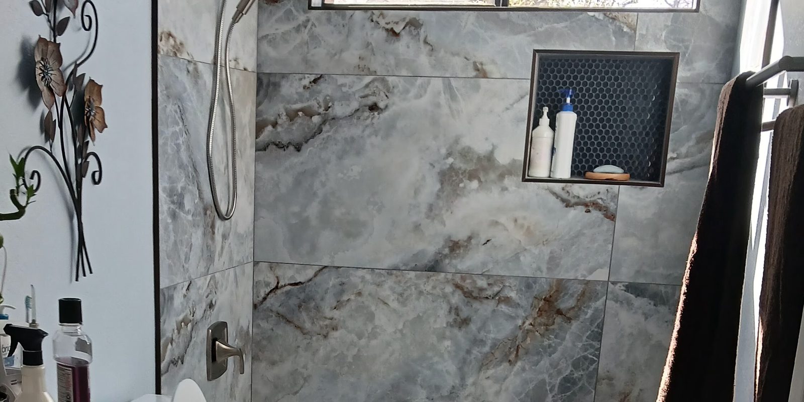 Shower wall in large-format marble-look tile with a tiled niche