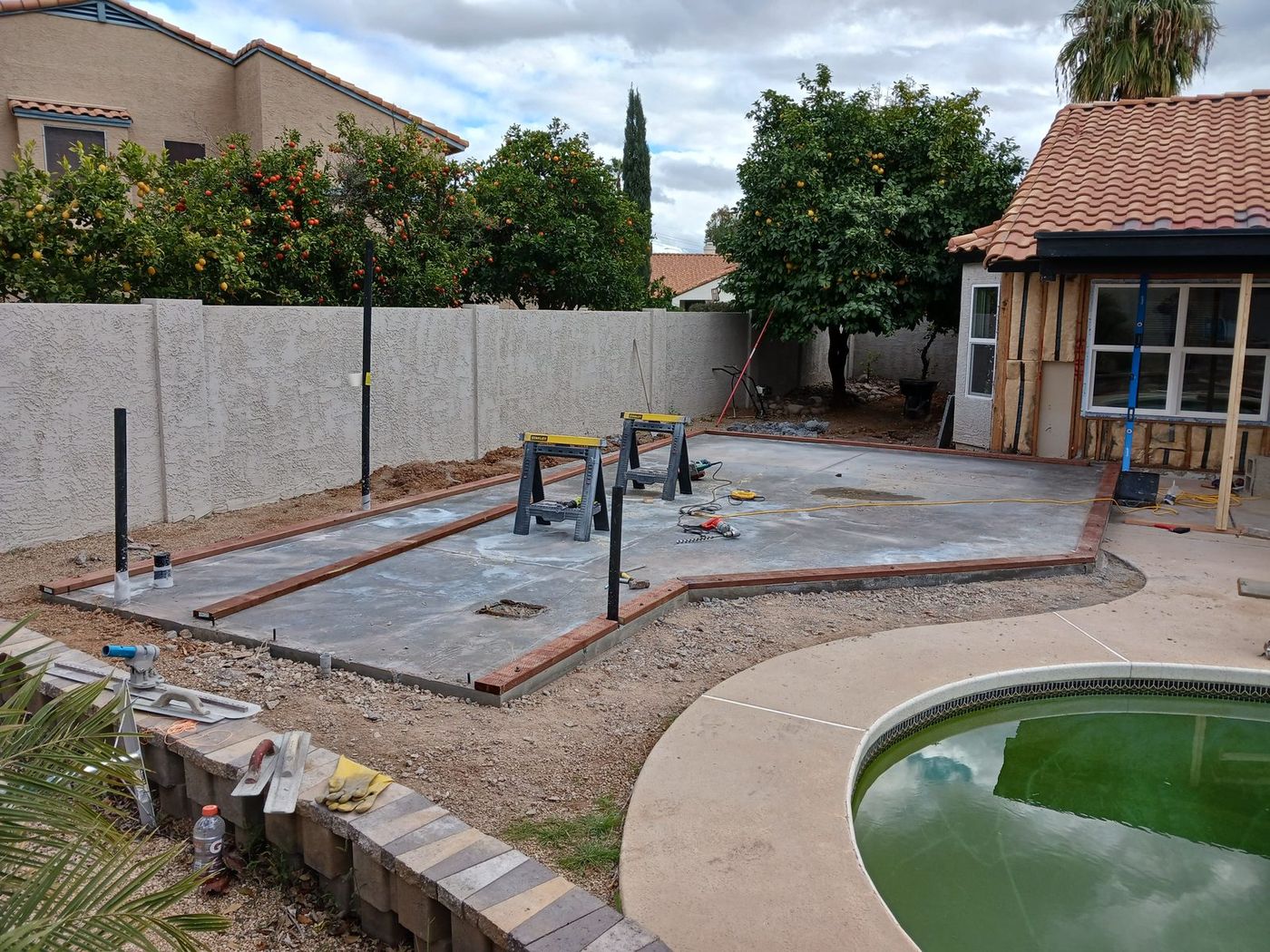 New backyard concrete slab with formed edges next to a pool